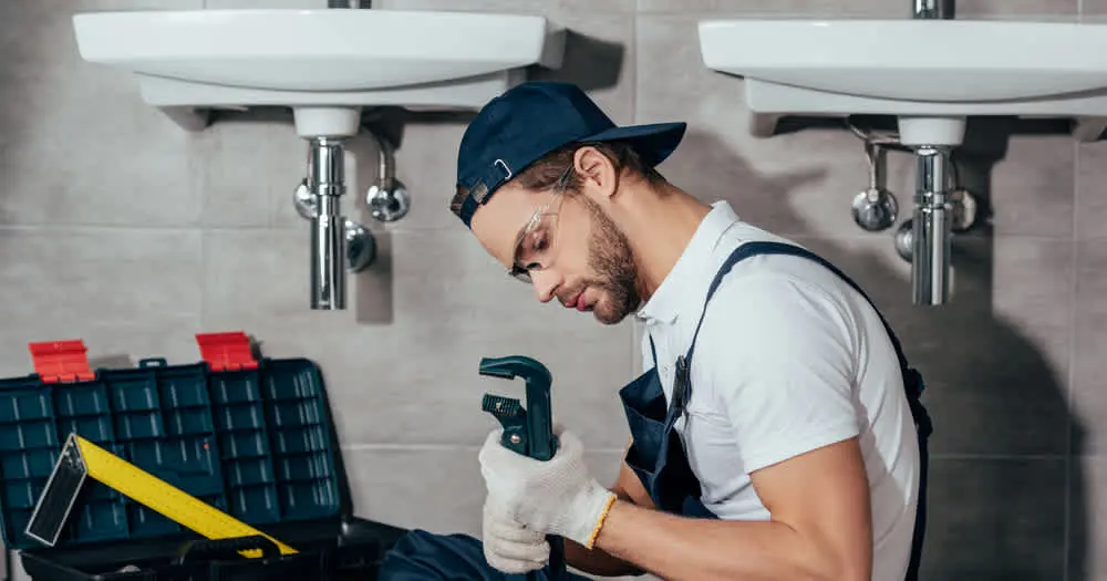 - Housecall Pro man with wrench under a sink