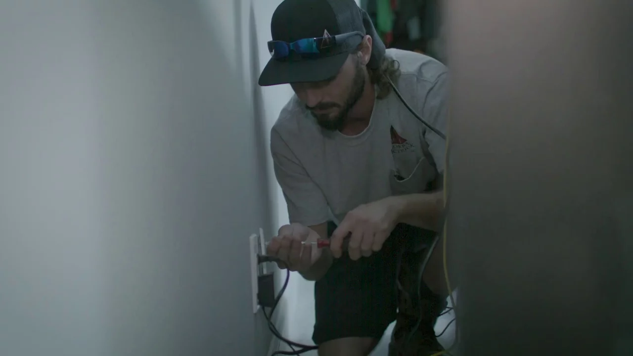 - Housecall Pro A man fixing an electrical outlet.