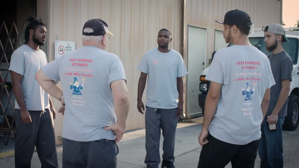 - Housecall Pro Cass Plumbing team huddle outside of warehouse