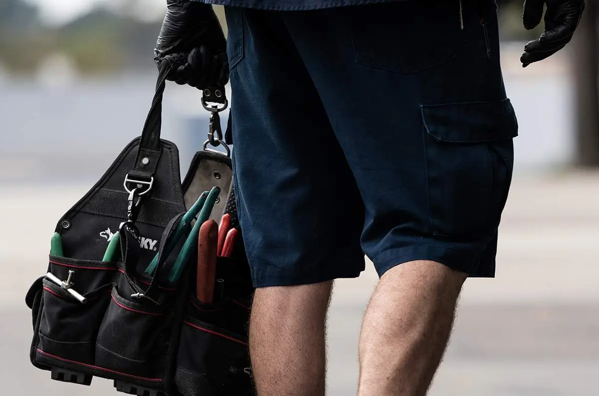 - Housecall Pro Plumber carrying black tool bag