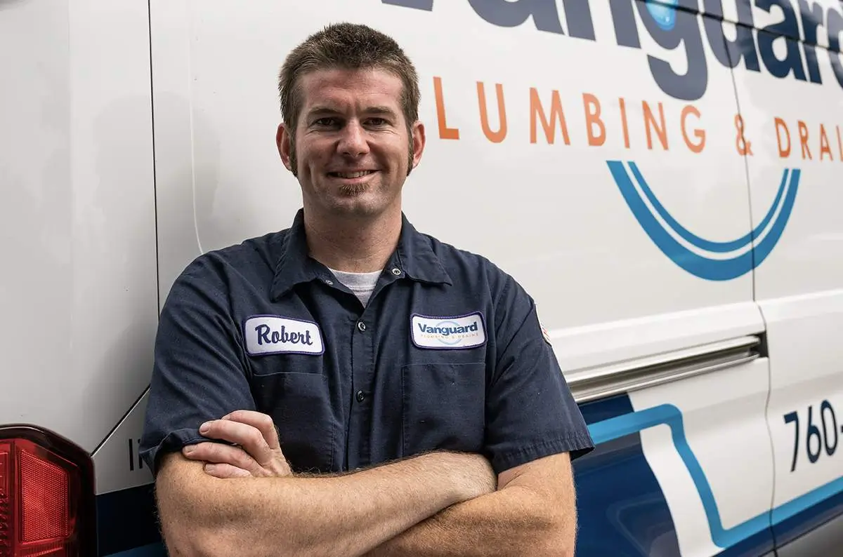 - Housecall Pro Plumber stands in front of work van