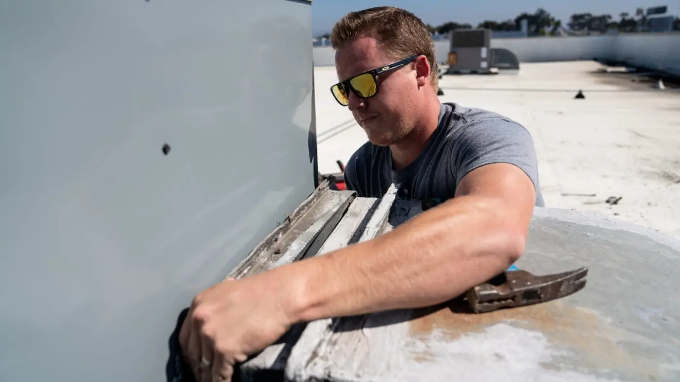 - Housecall Pro Man working on hvac unit on top of a building