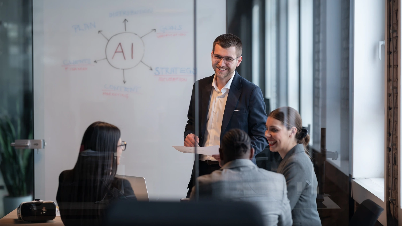 - Housecall Pro Business team in a meeting discussing AI strategy with a whiteboard presentation in a modern office.