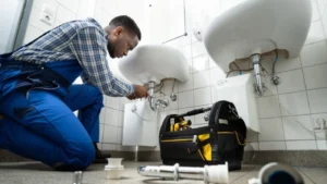 plumber fixing a leaking pipe in a bathroom