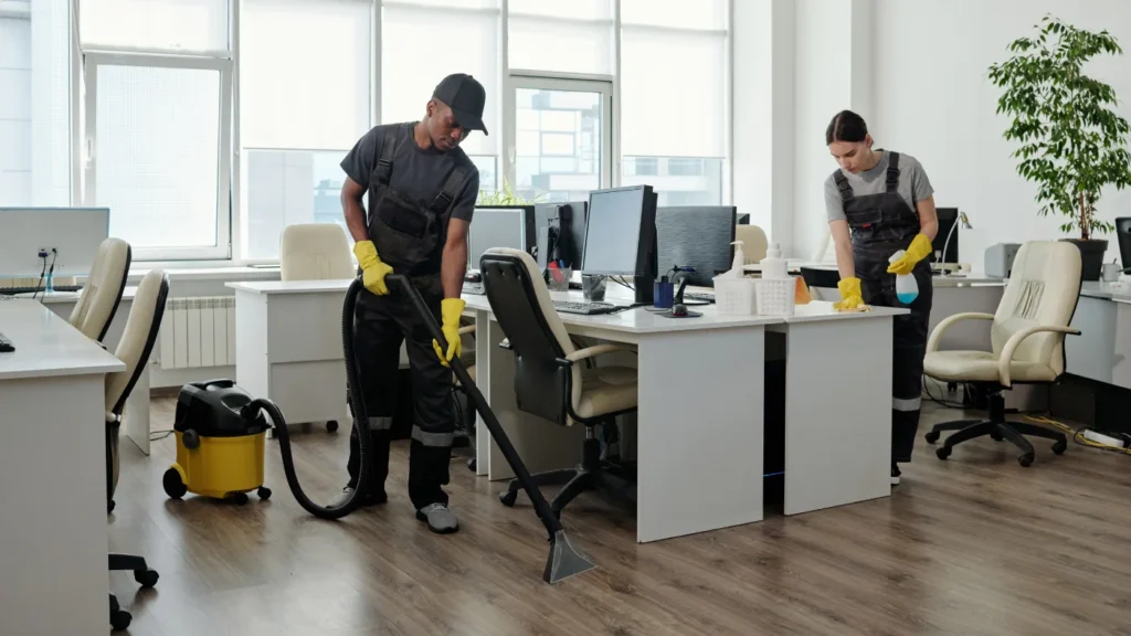 pro using vacuum cleaner for cleaning floor while a woman cleaning the desk