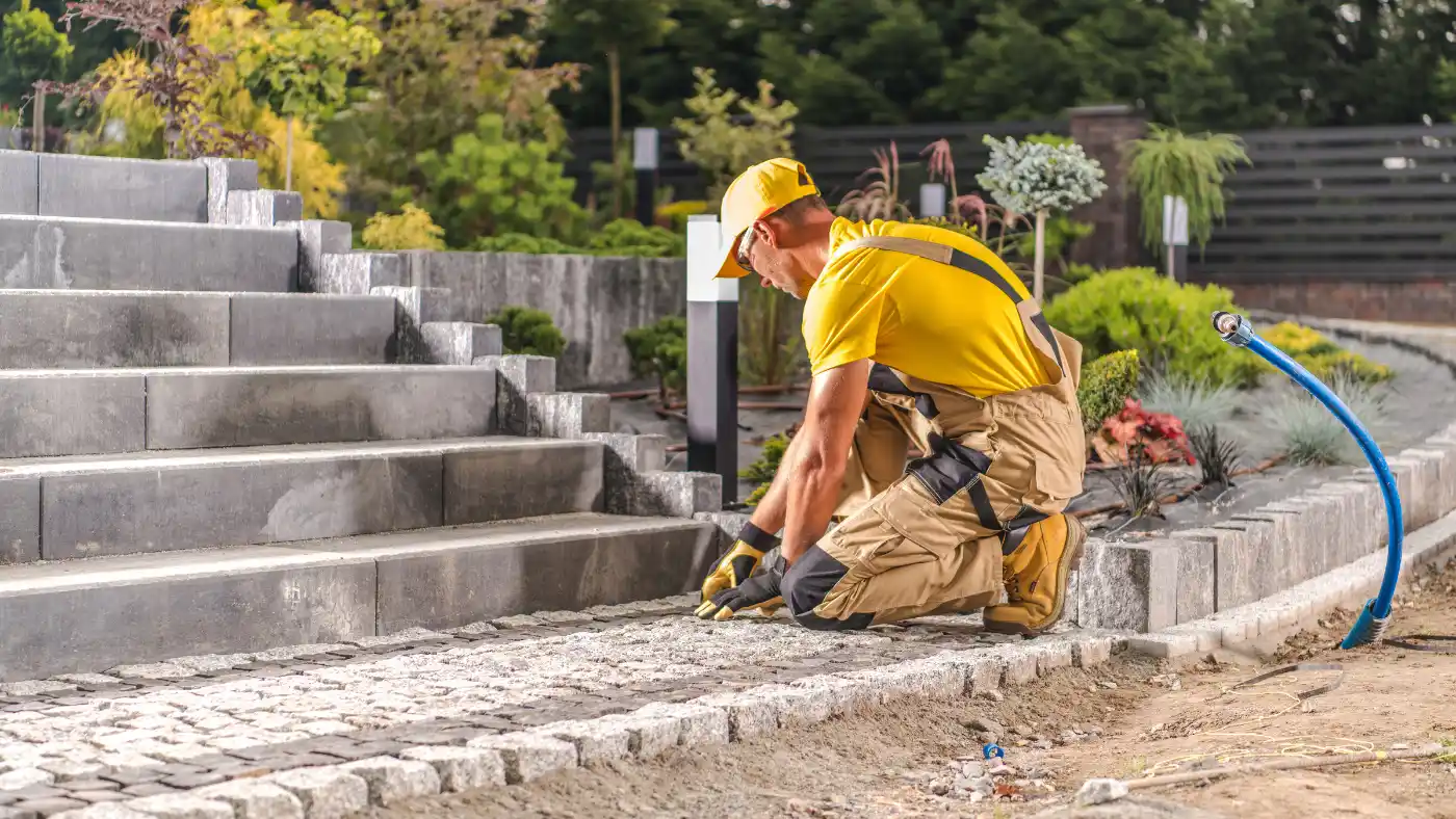 Pro worker laying cobblestones for a garden pathway in a landscaped area