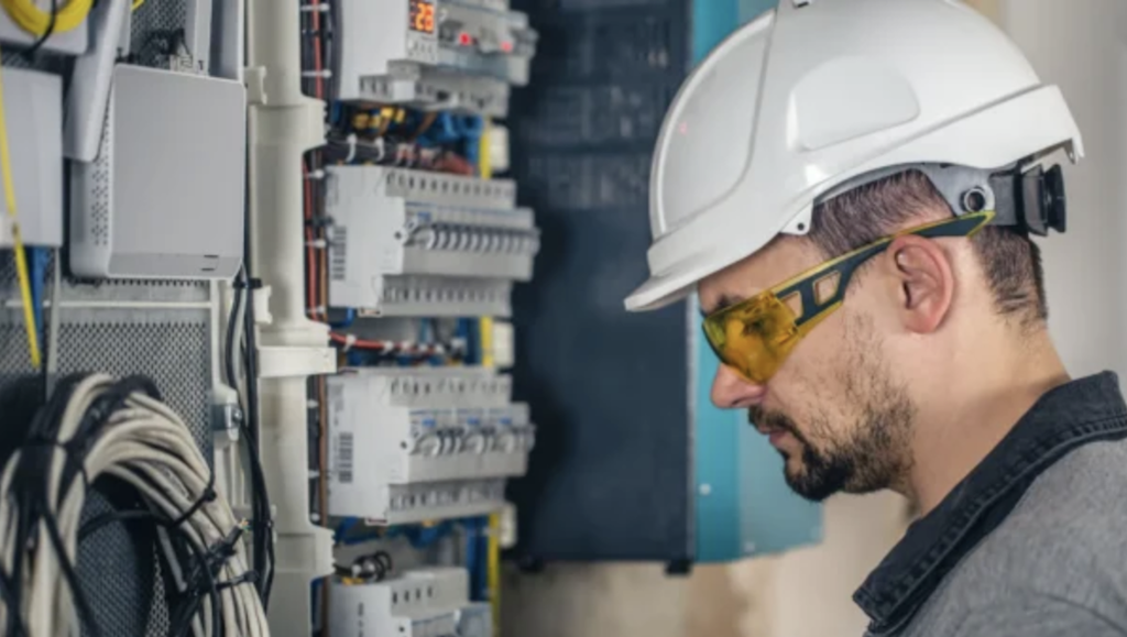 Electrician inspecting an electrical panel and circuit breakers while evaluating wiring and electrical components for an accurate job estimate and pricing.