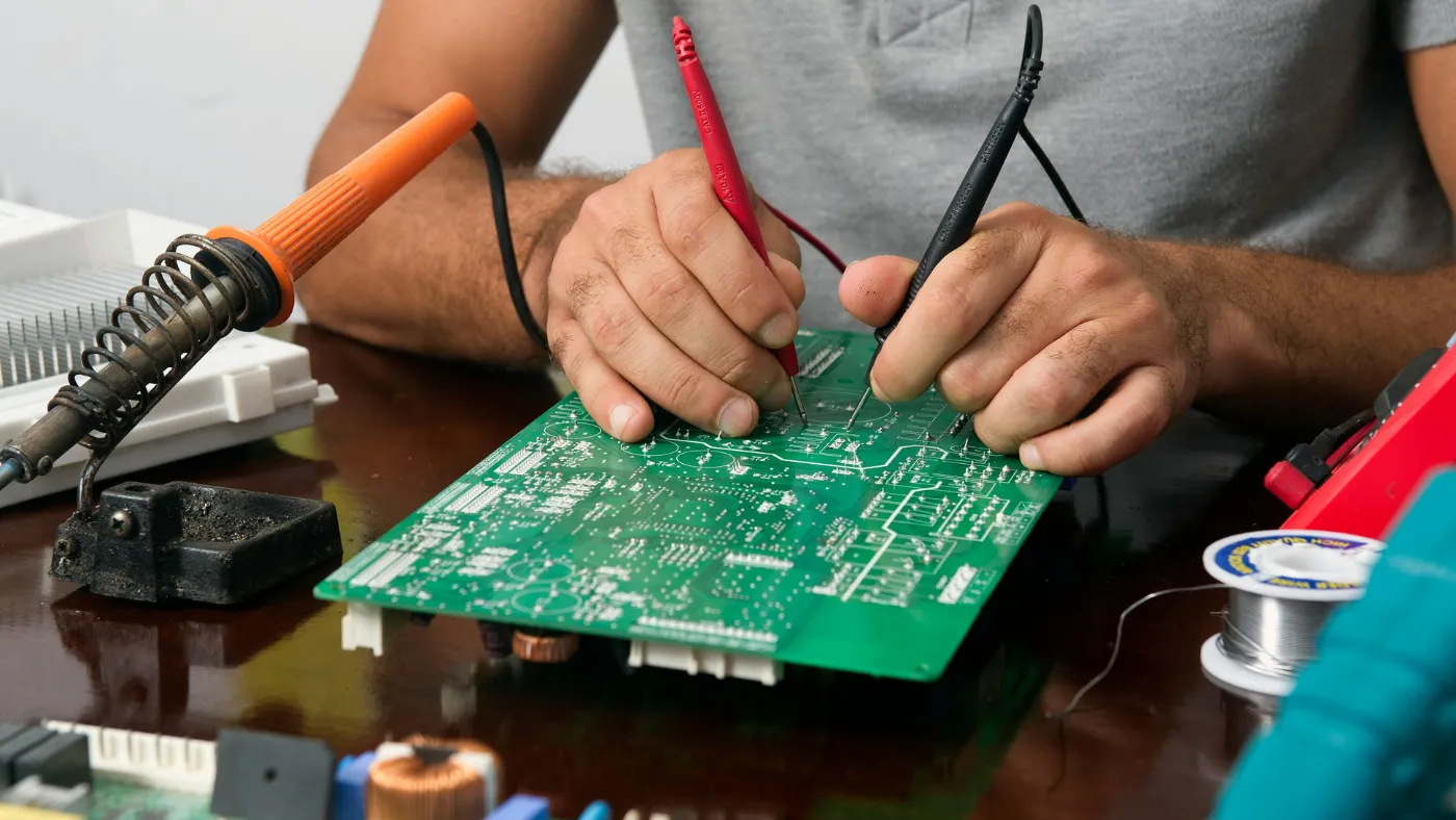 Appliance repair technician testing a circuit board with diagnostic probes